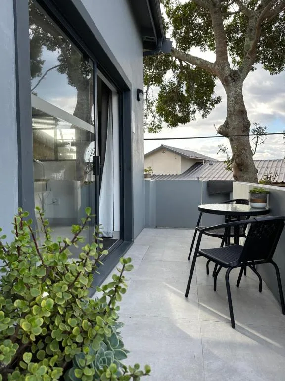 Modern patio with dining table, black chairs, and mature tree overhead