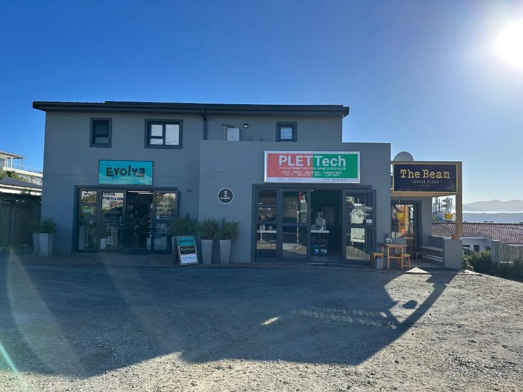Modern gray commercial building with retail shops and clear blue sky