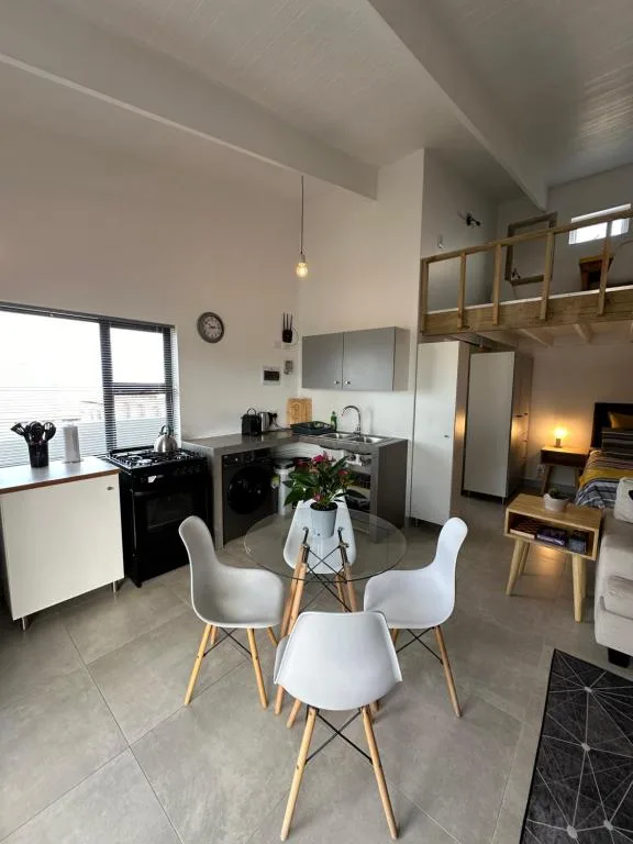 Modern kitchen and dining area with black stove, white chairs, and open shelving