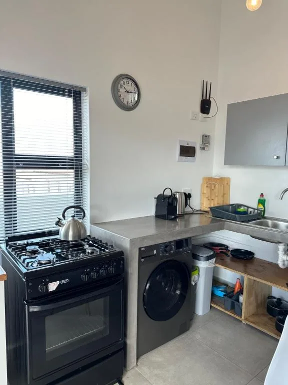 Modern kitchen with black gas stove, washing machine, and stainless steel countertop