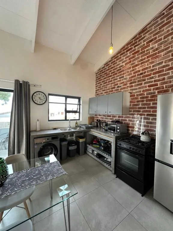 Modern kitchen with exposed brick wall, black appliances, stainless fridge