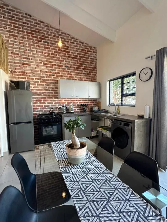 Modern kitchen with brick feature wall, black appliances, and dining table