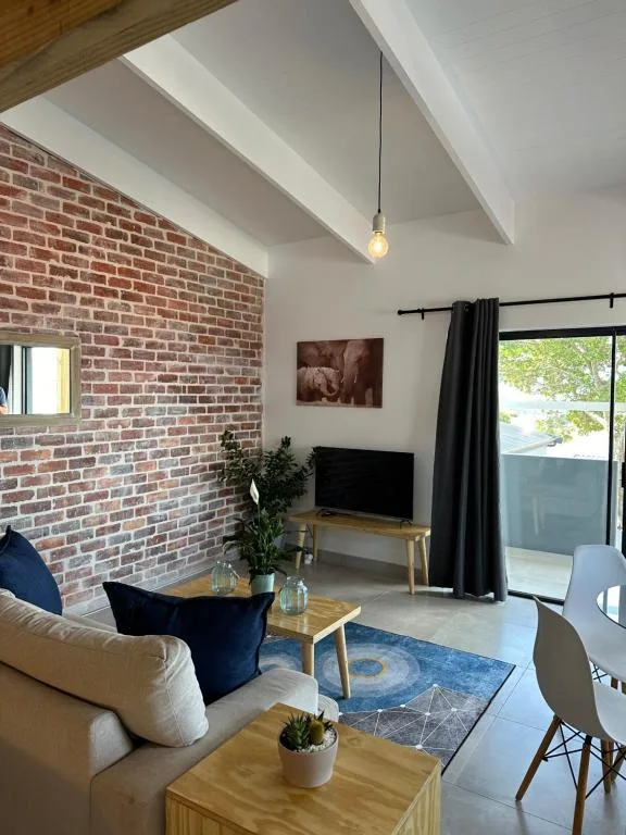 Modern lounge with exposed brick wall, pendant lighting, and sea views through glass doors