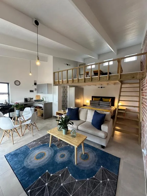 Modern open-plan lounge with sofa, loft bedroom, and kitchen area