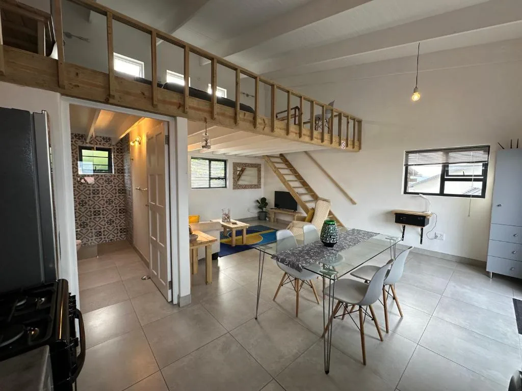Open-plan living area with dining table, sofa, and mezzanine bedroom above