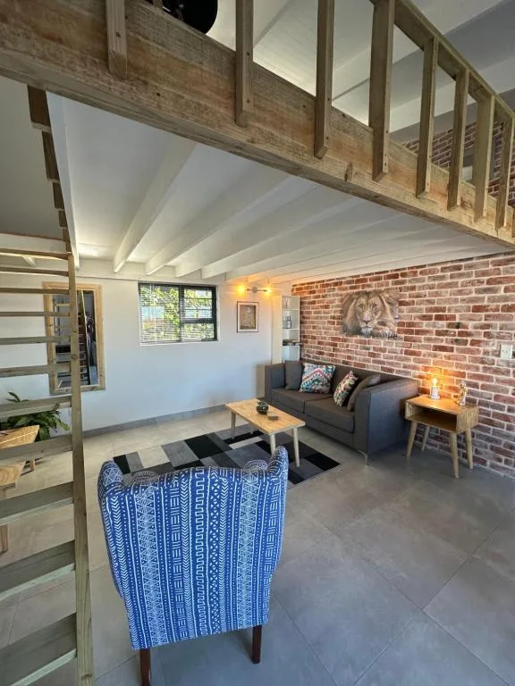 Open-plan lounge with exposed wooden beams, brick accent wall, and comfortable seating