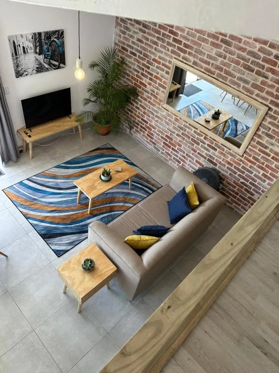 Modern living room with beige sofa, geometric rug, and exposed brick wall