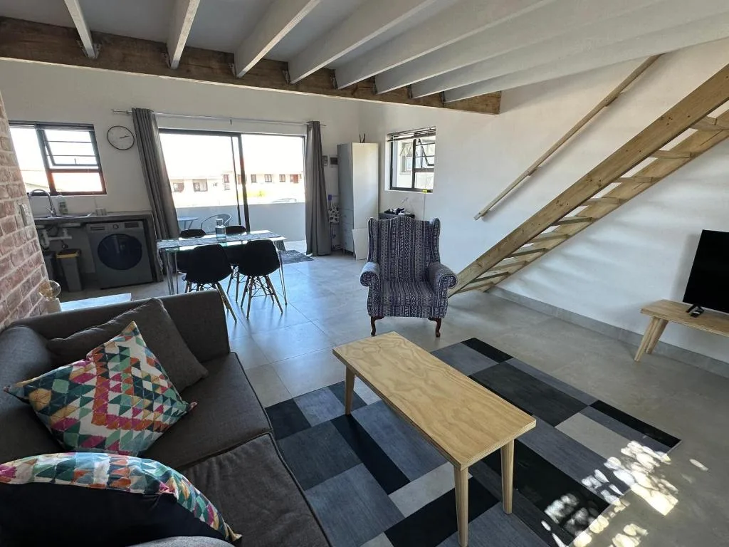 Open-plan lounge with gray sofa, wooden table, and staircase access