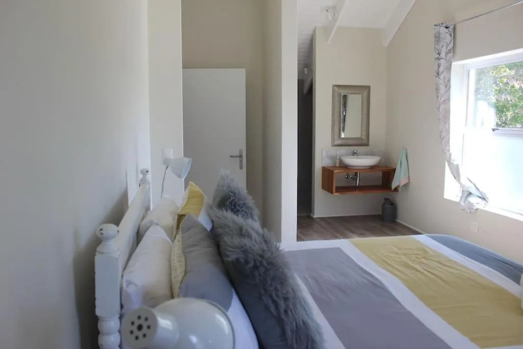 Bright bedroom with bed, en-suite bathroom visible through open doorway