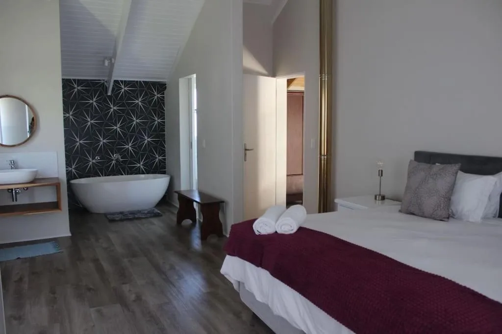 Spacious bedroom with ensuite bathroom featuring freestanding bathtub and geometric tile.