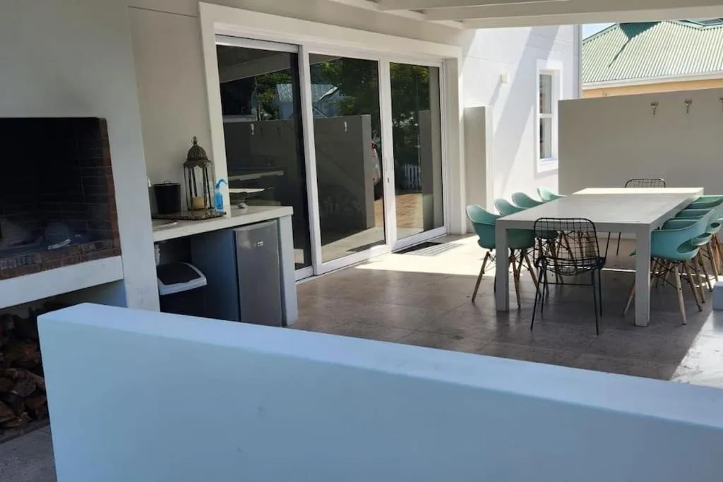 Modern outdoor patio with dining table, teal chairs, and ocean views