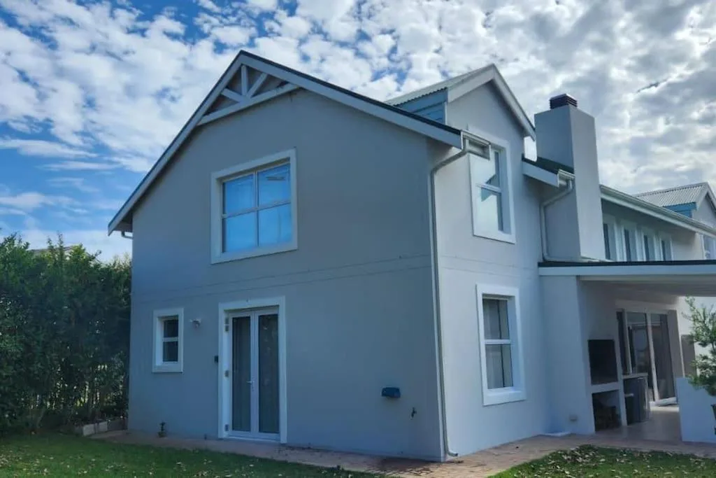 Modern white holiday home with blue accents and manicured garden