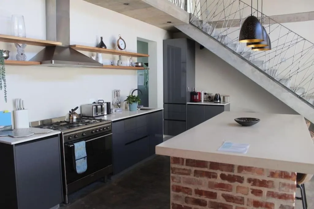 Modern kitchen with black cabinetry, gas stove, and brick island counter