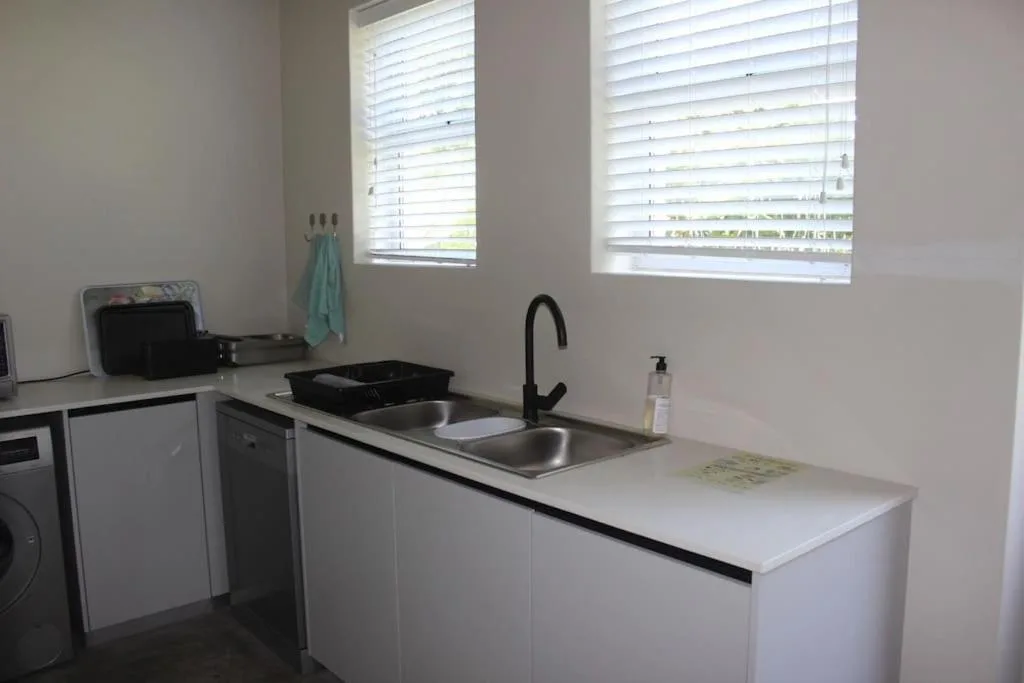 Modern white kitchen with stainless steel sink and black faucet
