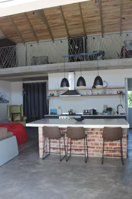 Modern kitchen with black pendant lights, brick island, and open shelving
