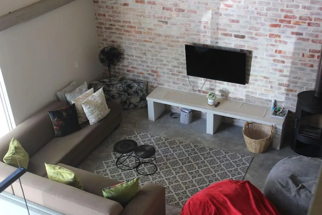 Modern living room with sofa, wall-mounted TV, and decorative brick accent wall