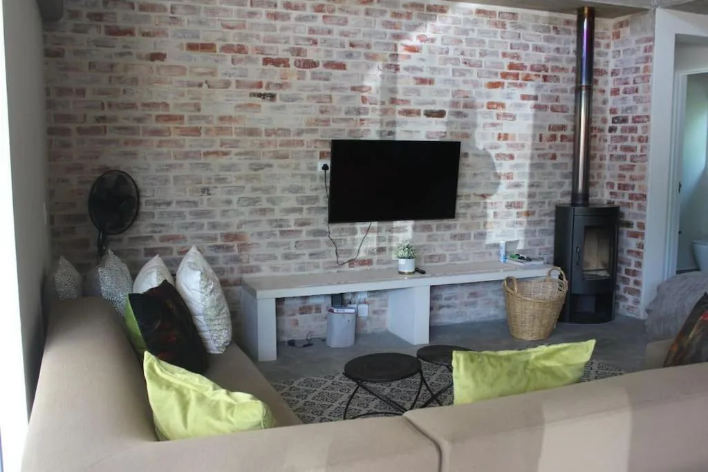 Modern lounge with brick accent wall, wall-mounted TV, and lime green accent pillows