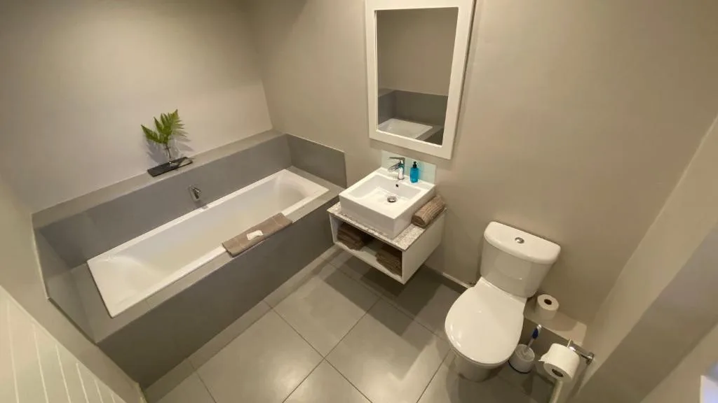 Modern bathroom with bathtub, vanity sink, toilet, and mirror