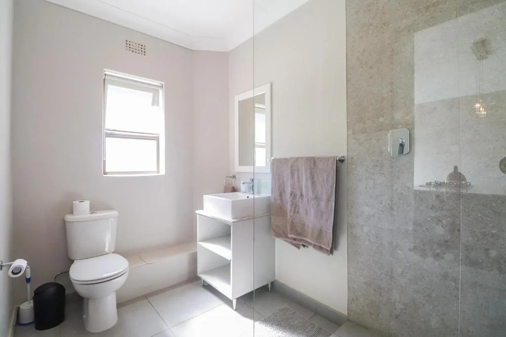 Modern bathroom with toilet, vanity sink, and walk-in shower enclosure