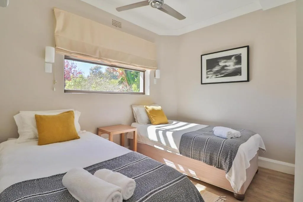 Bright bedroom with twin beds, natural light, and garden views through window