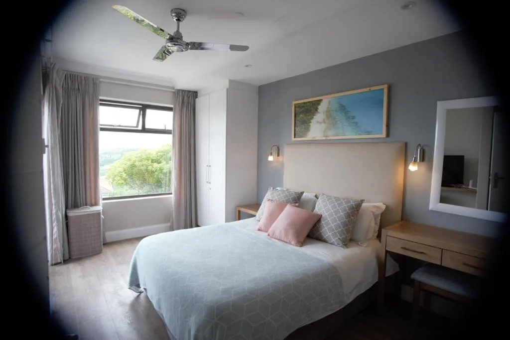 Spacious bedroom with queen bed, modern furnishings, and garden view windows