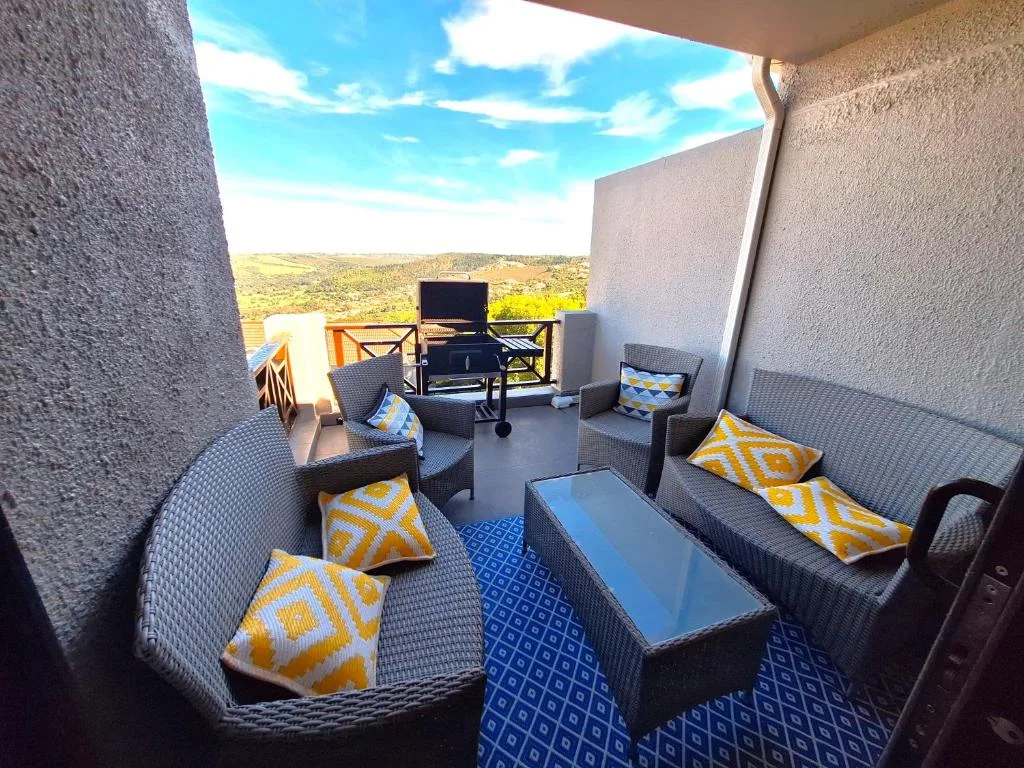 Covered outdoor patio with rattan seating and scenic countryside views