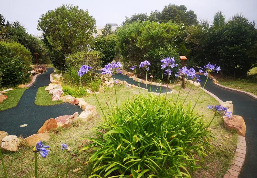 Landscaped garden with purple flowers, winding pathways, and mature trees