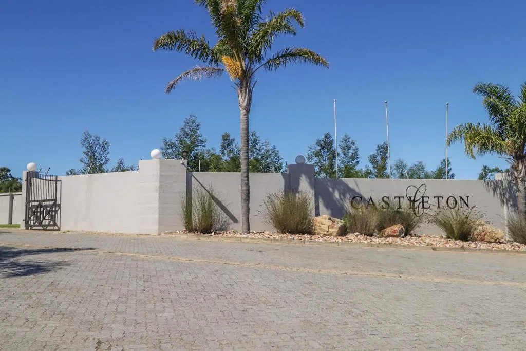Modern white entrance wall with Castleton signage and palm trees