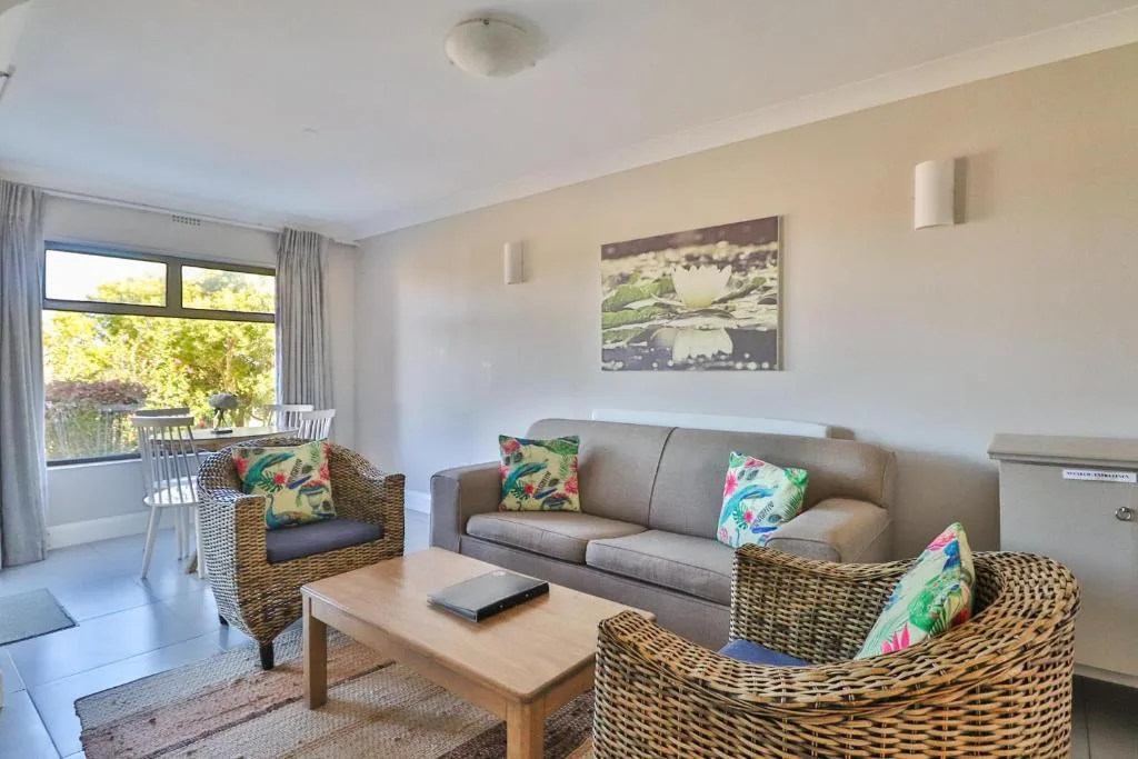 Bright lounge with gray sofa, wicker armchairs, and garden views