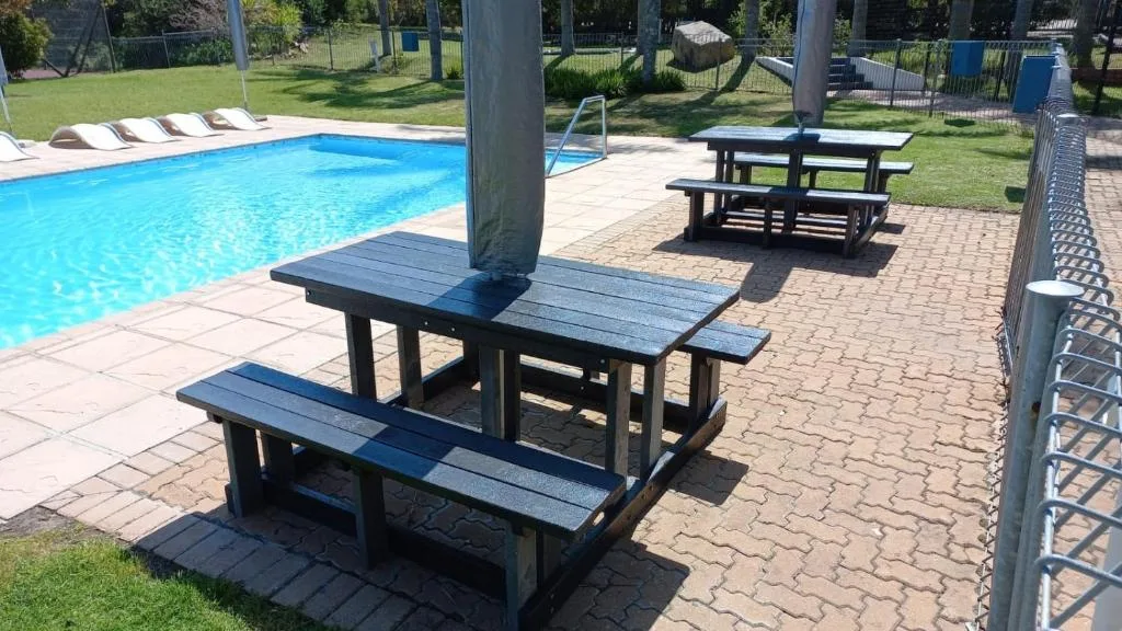 Swimming pool with lounge chairs and picnic tables in sunny garden area