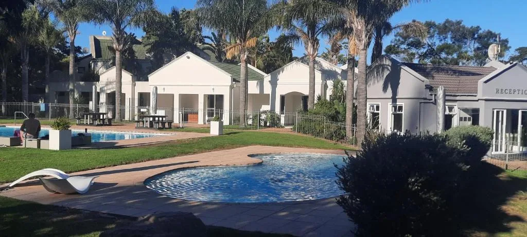 Resort swimming pool with palm trees and white buildings in background
