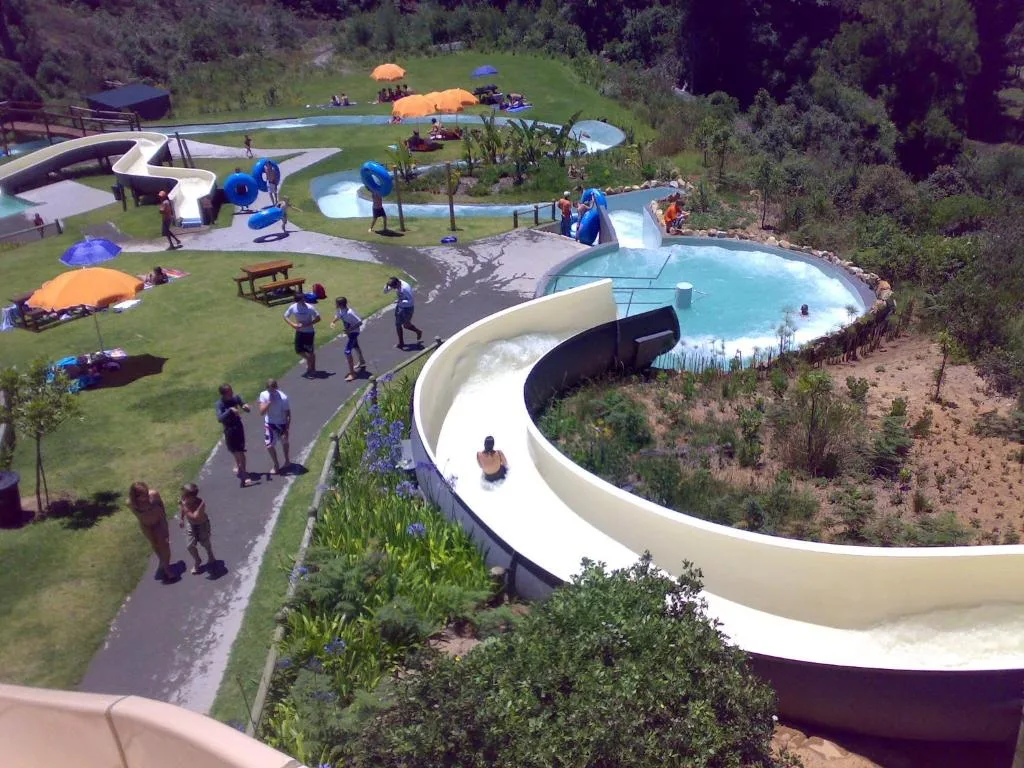 Aerial view of water park with multiple pools, slides, and green gardens