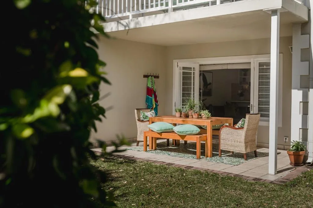 Covered patio with wooden table, wicker chairs, and potted plants
