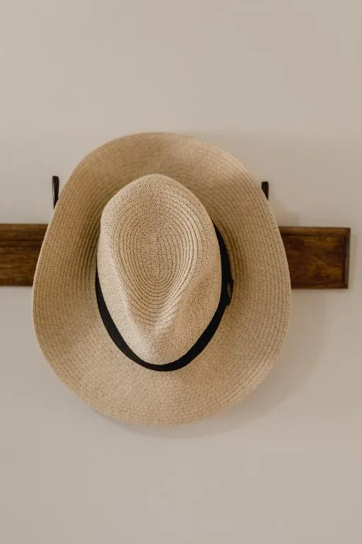 Two straw hats hanging on wooden wall-mounted rack indoors