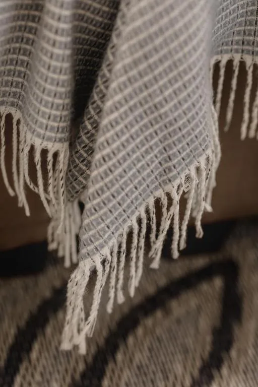 Close-up of cream textured throw blanket with fringed edges