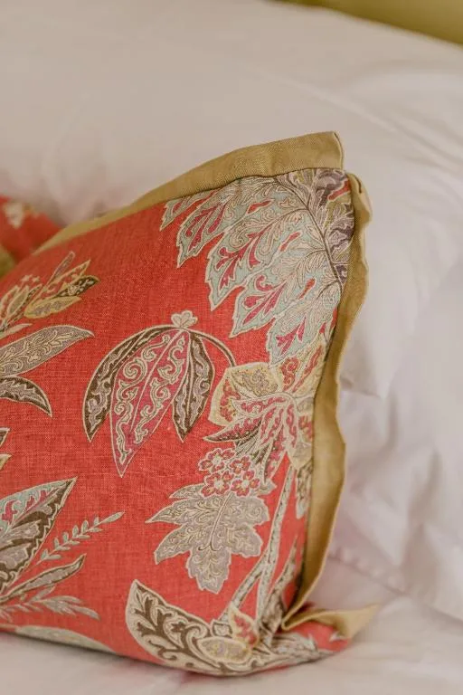 Decorative red and gold patterned pillow on white bedding