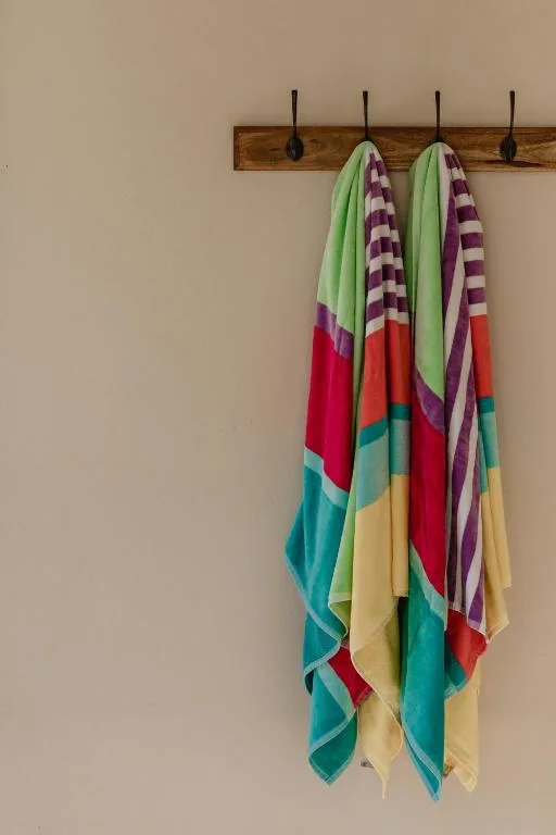 Colorful striped towels hanging from wooden rack on wall
