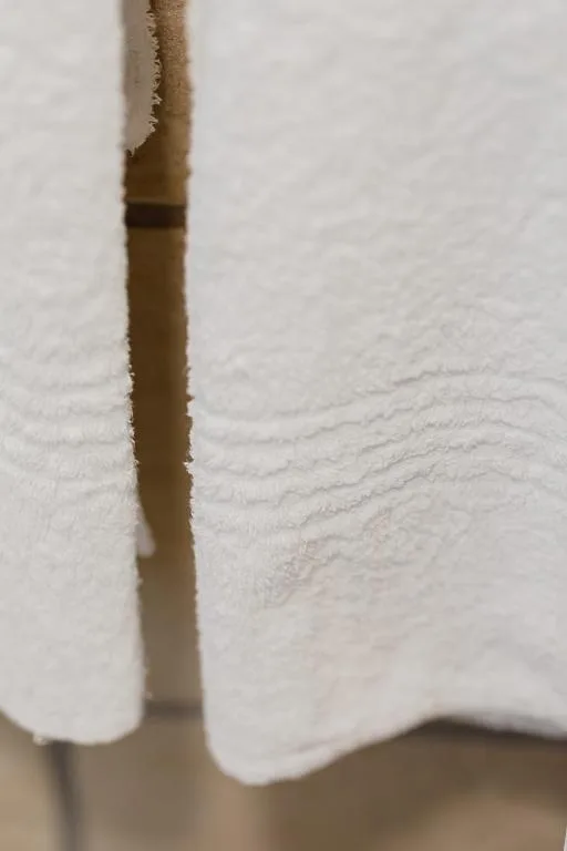 Close-up of white textured curtain fabric with wooden curtain rod