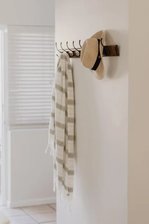 Wall-mounted hooks holding a straw hat and checkered scarf indoors