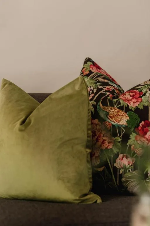 Decorative cushions with floral and solid green fabrics on a sofa