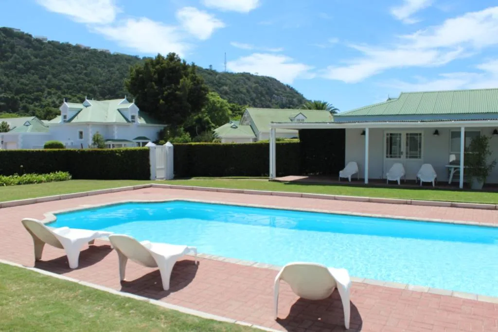 Sparkling blue swimming pool with white loungers and mountain views