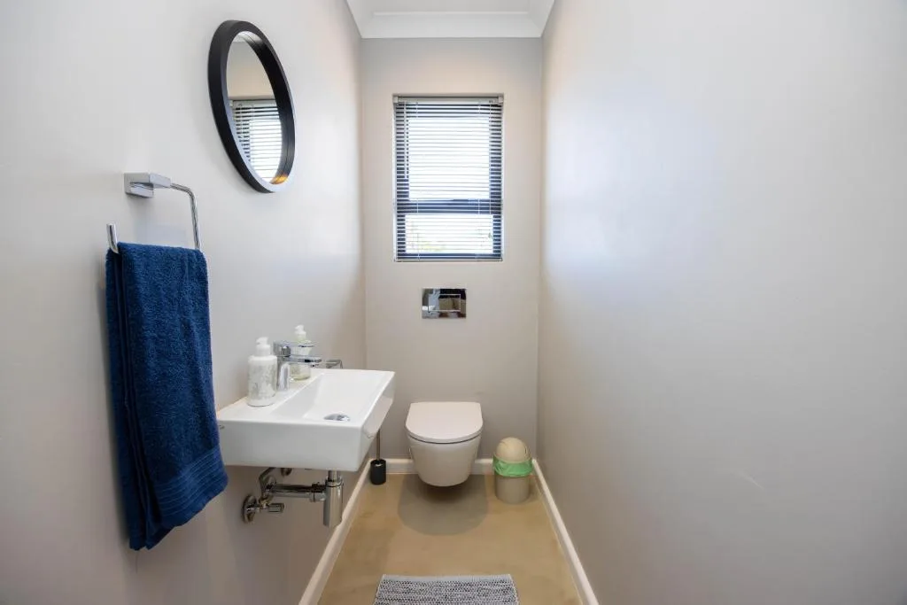 Modern bathroom with white vanity, toilet, and blue towel rail