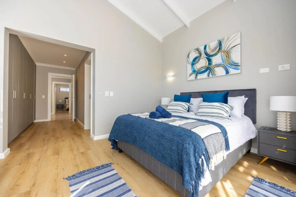 Bright modern bedroom with blue and white bedding, skylights, and wooden flooring