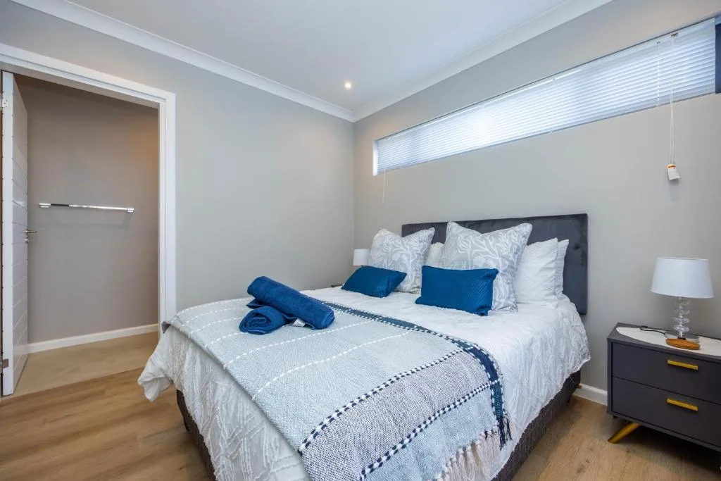 Spacious bedroom with queen bed, blue accents, and ensuite bathroom door