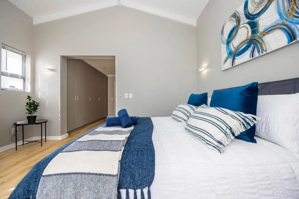 Bright modern bedroom with blue accents and wooden flooring throughout