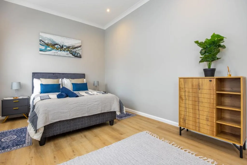 Bright bedroom with double bed, blue accents, wooden furniture and potted plant