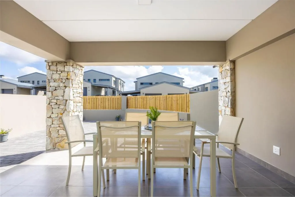 Covered patio with dining table and chairs overlooking residential area