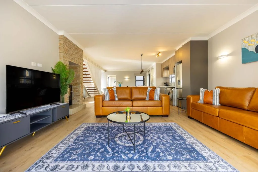 Spacious lounge with orange leather sofas and flat-screen TV