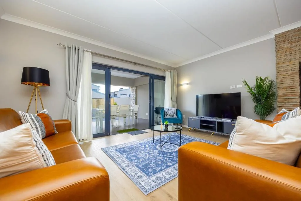 Modern lounge with orange leather sofas and sliding glass doors to deck