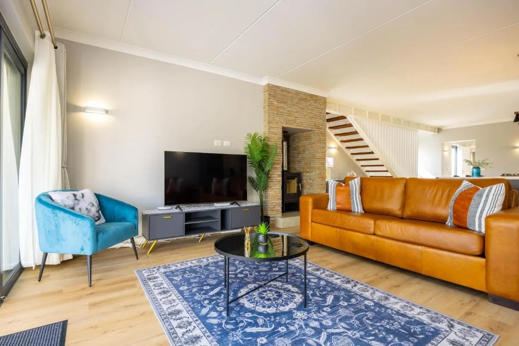 Open-plan lounge with orange leather sofa and blue armchair, TV entertainment unit